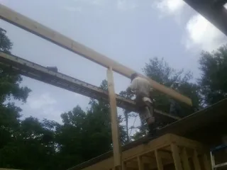 Carpenter setting a ridge beam over a new addition frame — Ice Dam Removal by Roofing Brothers in Simms