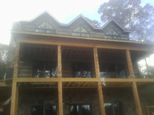 Dormers and porch framing on a large log home under construction — Roof Coating work by our crew in Simms