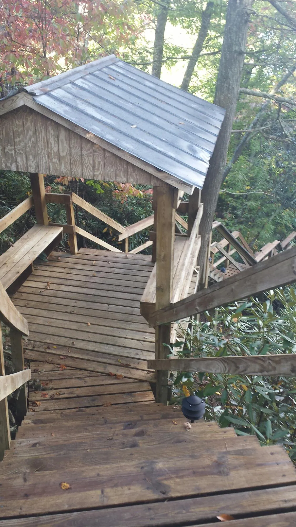 Metal roofed shelter over wooden steps on a wooded walkway — Skylight Repair & Installation work by our crew in Simms