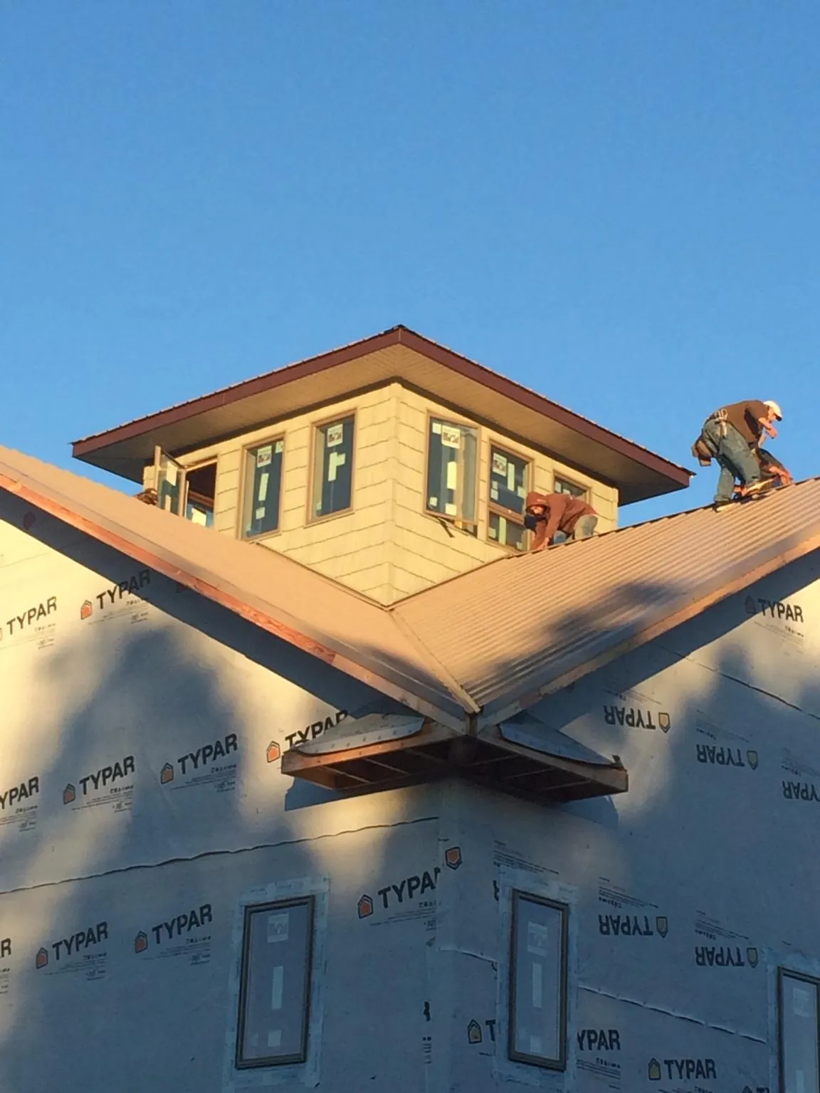 Roofers working around a rooftop cupola on a new metal roof at sunset — Roof Waterproofing in Simms by Roofing Brothers